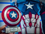Captain America shield speaker on its base in front of a Captain America suit