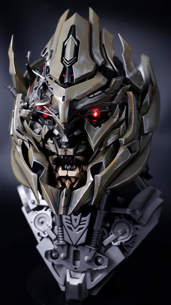 Megatron helmet with red eye lit, front three-quarter view on a Decepticon display base